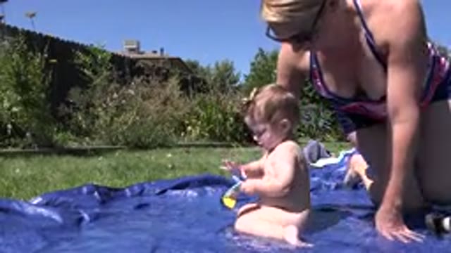 WESTMINSTER COLORADO-2015: Woman And Child Play In Blue Waterside Outside Under Sun