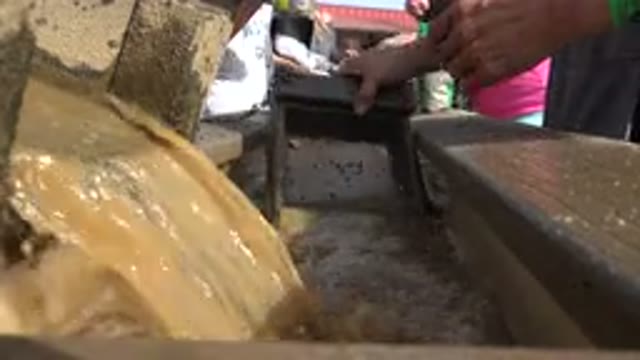 BRIGHTON COLORADO-2015: Workers Processing Muddy Water in Sunny Outdoor Area