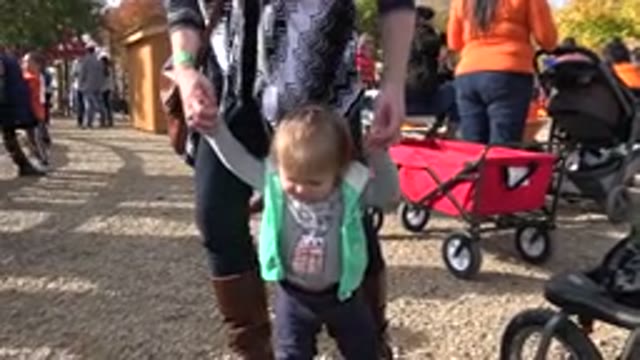 BRIGHTON COLORADO-2015: Woman In Boots Holds Small Child's Arms To Help Her Walk