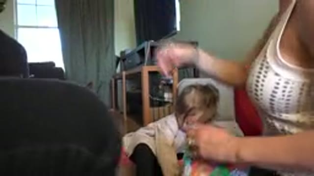 WESTMINSTER COLORADO-2015: Woman Opening Packaging While Blonde Baby Plays With