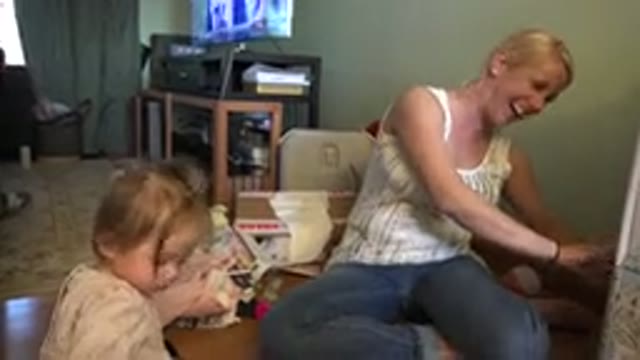 WESTMINSTER COLORADO-2015: A Laughing Mother Unwrapping a Gift Beside Her Daughter