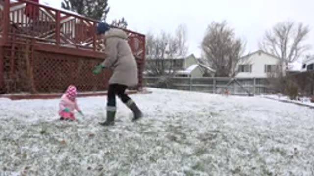 WESTMINSTER COLORADO-2015: Snowing Outside A Mother Is Helping Her Daughter To Play