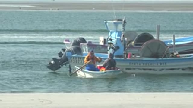 LA BOCANA BCS MEXICO-2022: Two People Rowing a Small Boat Near a Larger Vessel