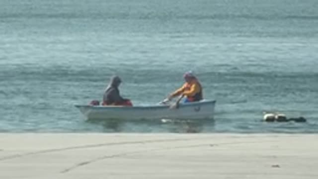 LA BOCANA BCS MEXICO-2022: Two People Fishing From a Small Boat at the Beach