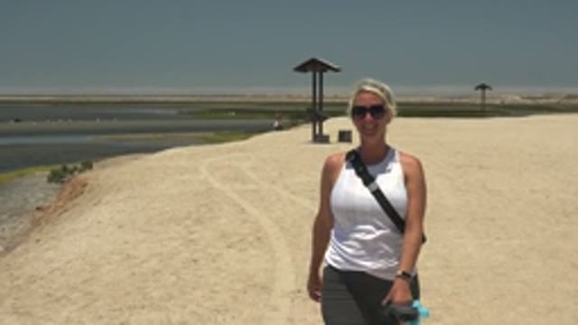 GUERRERO NEGRO BCS MEXICO-2022: Woman Approaching Camera on Sandy Riverside Path