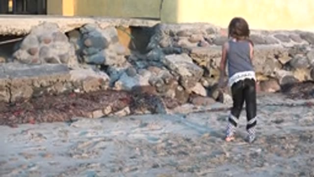 SAN CARLOS BCS MEXICO-2022: Girl Playing on Sandy Beach Near Stone Wall