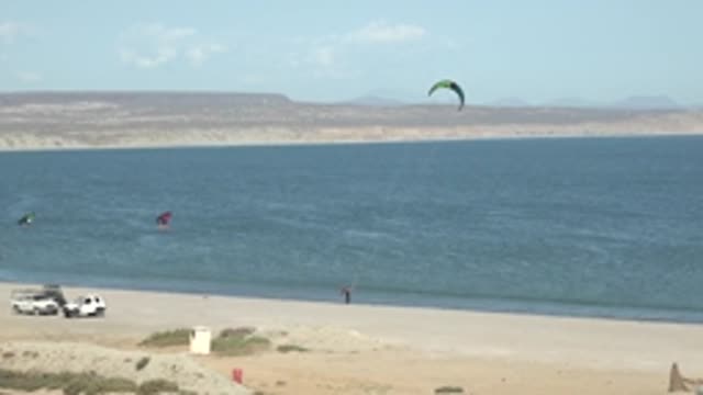 SAN JUANICO BCS MEXICO-2022: Kite Surfers on a Sandy Beach with Distant Hills
