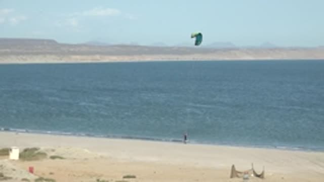 SAN JUANICO BCS MEXICO-2022: Kite Surfer Moving Along Sandy Shore