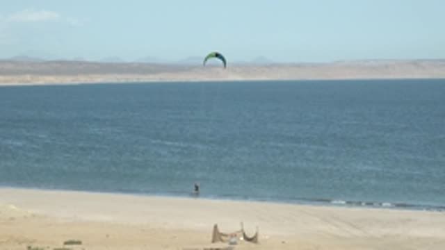 SAN JUANICO BCS MEXICO-2022: Kitesurfer Moving Along Sandy Shore by Calm Ocean