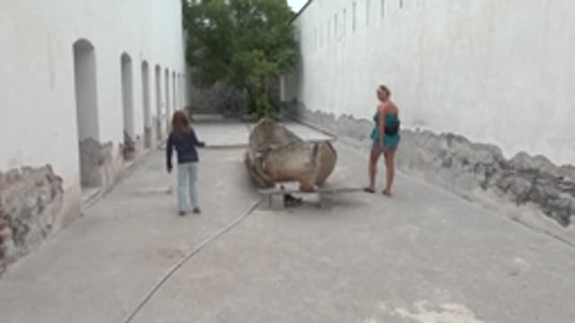 MULEGE BCS MEXICO-2022: Two People Approaching a Wooden Boat in a Courtyard