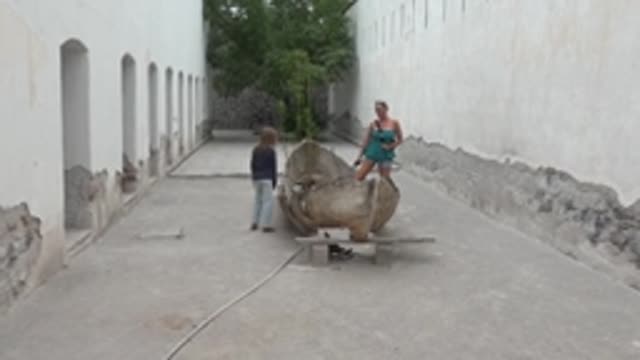 MULEGE BCS MEXICO-2022: Child and Adult Interacting with Large Shell Sculpture in Courtyard