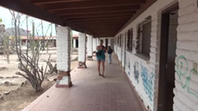 MULEGE BCS MEXICO-2022: Two People Walking Along a Desert Building Corridor