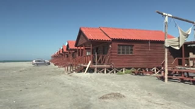 LA BOCANA BCS MEXICO-2022: Red Wooden Beach Huts with Bird Flying Away