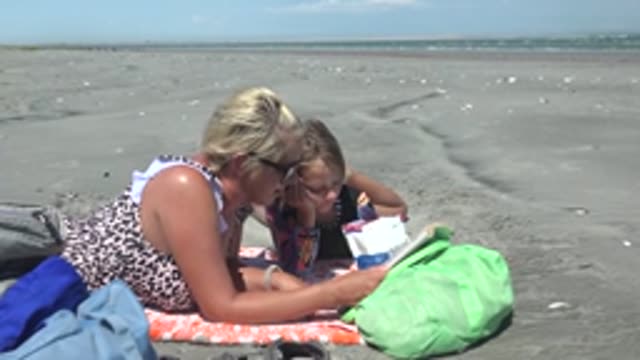 LA BOCANA BCS MEXICO-2022: Woman and Child Reading Together on Sandy Beach