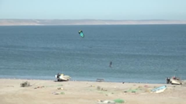 SAN JUANICO BCS MEXICO-2022: Kite Surfer Moving Across Ocean Near Sandy Beach