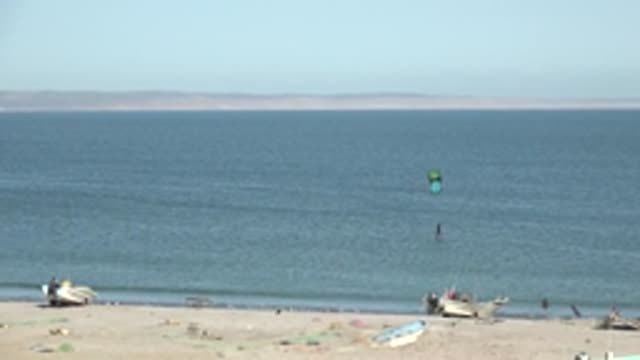 SAN JUANICO BCS MEXICO-2022: Kitesurfer Gliding over Calm Ocean near Sandy Beach