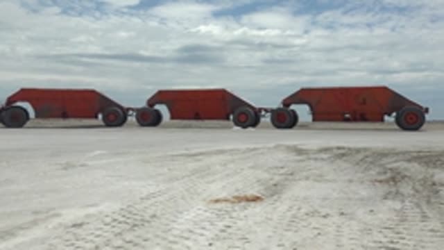 GUERRERO NEGRO BCS MEXICO-2022: Red Mine Carts Moving Across Sandy Ground