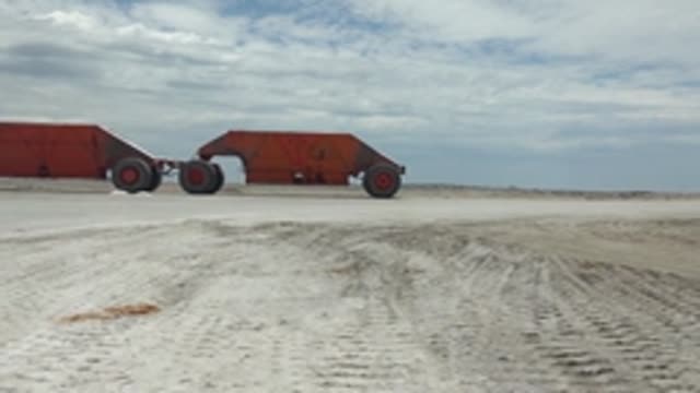 GUERRERO NEGRO BCS MEXICO-2022: Rusted Red Vehicle Moving Across Sandy Terrain