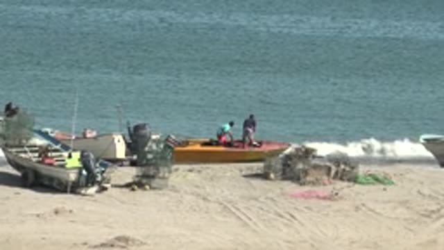 SAN JUANICO BCS MEXICO-2022: Fishermen on a Small Boat at the Sandy Shore