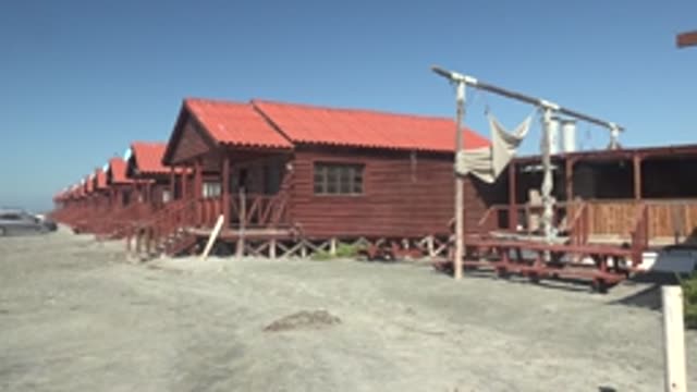 LA BOCANA BCS MEXICO-2022: Row of Red Wooden Cabins with Moving Car