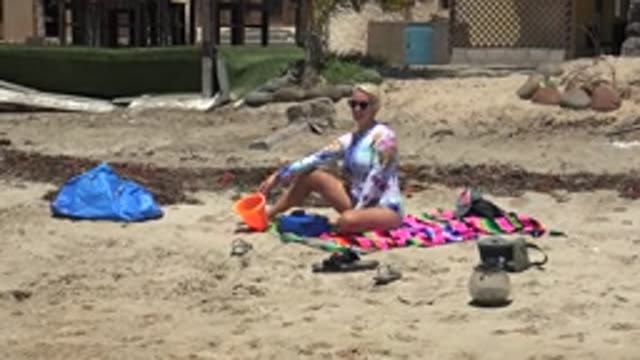 SAN CARLOS BCS MEXICO-2022: Woman Adjusting Orange Bucket on Sandy Beach