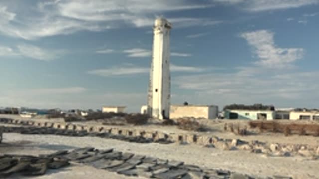 GUERRERO NEGRO BCS MEXICO-2022: Lighthouse on Sandy Beach with Rock Formations