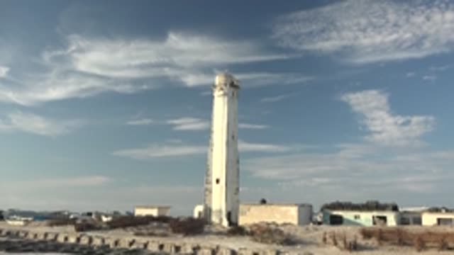 GUERRERO NEGRO BCS MEXICO-2022: Lighthouse on Sandy Shore with Drifting Clouds