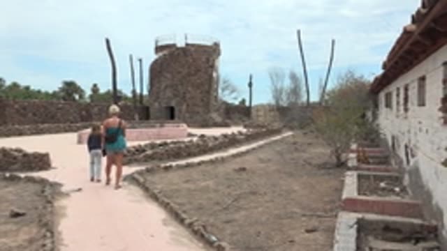 MULEGE BCS MEXICO-2022: Two People Walking near Ancient Stone Tower