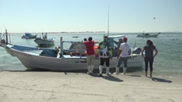 LA BOCANA BCS MEXICO-2022: People Unloading a Boat on the Sandy Beach
