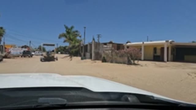 BAJA CALIFORNIA MEXICO-2022: Car Driving Through Dusty Residential Area with Dog