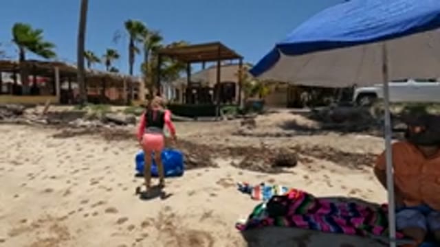 BAJA CALIFORNIA MEXICO-2022: Girl Carrying Blue Bag on Sandy Beach