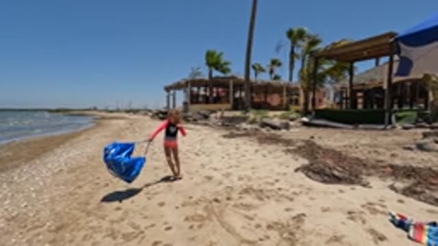 BAJA CALIFORNIA MEXICO-2022: Girl Carrying Blue Bag Along Sandy Beach