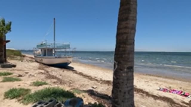 BAJA CALIFORNIA MEXICO-2022: Beach Scene with Boat and Person near Towel