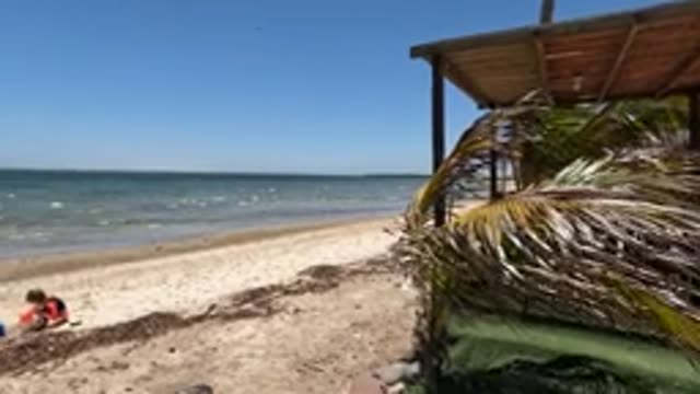 BAJA CALIFORNIA MEXICO-2022: Child Arranging Towel and Bag on Sandy Beach