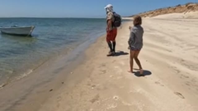 BAJA CALIFORNIA MEXICO-2022: Beachgoers Walking near Shore with Small Boat