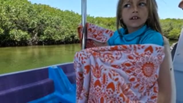 BAJA CALIFORNIA MEXICO-2022: Child Wrapped in Blanket on Boat near Mangroves