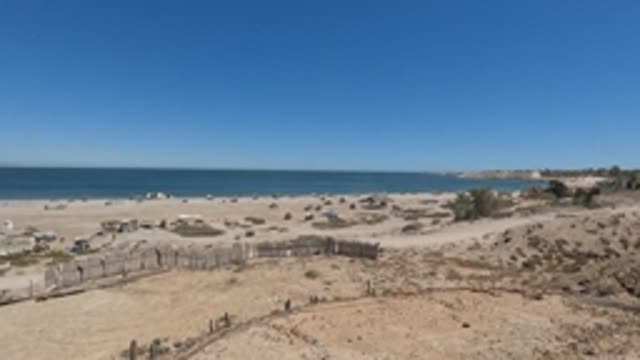 BAJA CALIFORNIA MEXICO-2022: Sandy Dune Overlooking Beach with People and Umbrellas