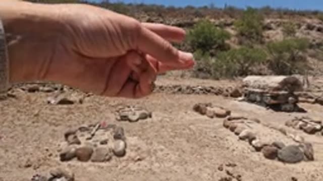 BAJA CALIFORNIA MEXICO-2022: Hand Pointing at Stone Arrangements in Arid Landscape