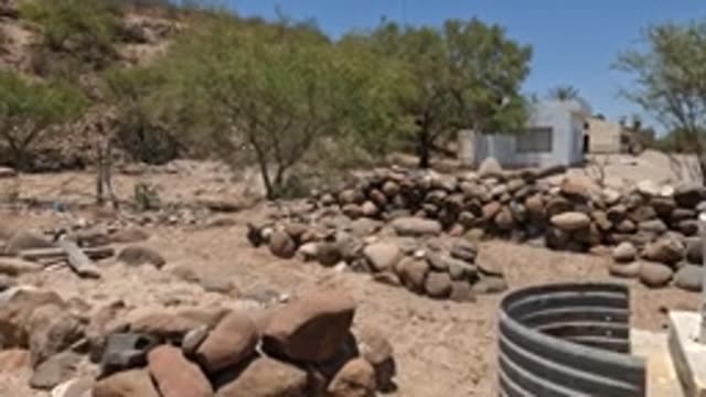 BAJA CALIFORNIA MEXICO-2022: Person Walking Past Rocky Garden with House