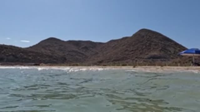 BAJA CALIFORNIA MEXICO-2022: Gentle Ocean Waves at Sandy Beach with Distant Hills