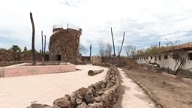 BAJA CALIFORNIA MEXICO-2022: Person Walking Through Courtyard with Stone Tower
