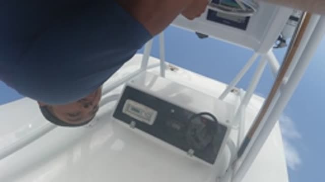 BAJA CALIFORNIA MEXICO-2022: Man Adjusting Controls on a White Boat