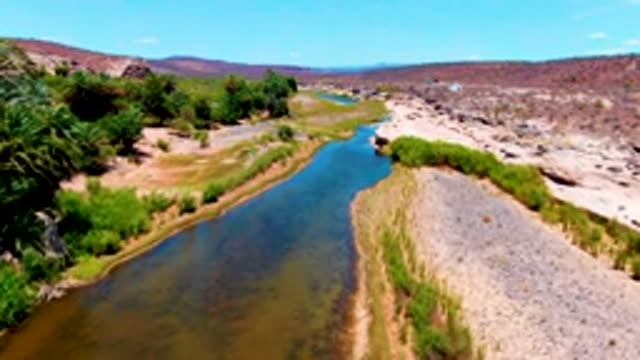 SAN JUANICO BCS MEXICO-2022: Flowing River in Arid Rocky Terrain with Sparse Vegetation