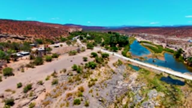 SAN JUANICO BCS MEXICO-2022: Desert River Flowing Past Small Settlement and Bridge