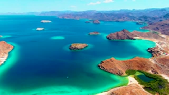PLAYA SANTISPAC BCS MEXICO-2022: Boat Moving Through Turquoise Waters Between Rocky Islands