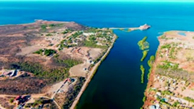 MULEGE BCS MEXICO-2022: Vehicles Moving Along a Coastal Road Beside a Narrow Waterway