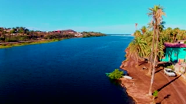 MULEGE BCS MEXICO-2022: Car Driving Along Canal Shore with Palm Trees