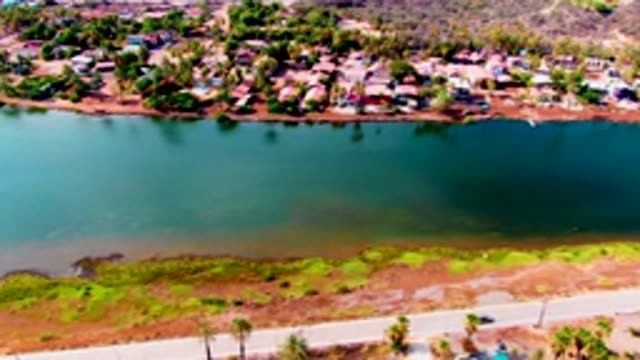 MULEGE BCS MEXICO-2022: Car Moving Along Road Beside Residential Waterway