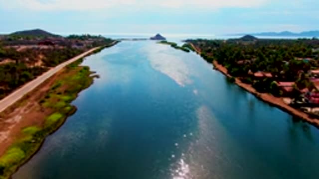 MULEGE BCS MEXICO-2022: Sunlight Glinting on a Calm Waterway with Road and Trees