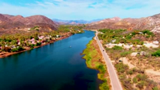 MULEGE BCS MEXICO-2022: Vehicle Moving Along Riverfront Road near Mountains